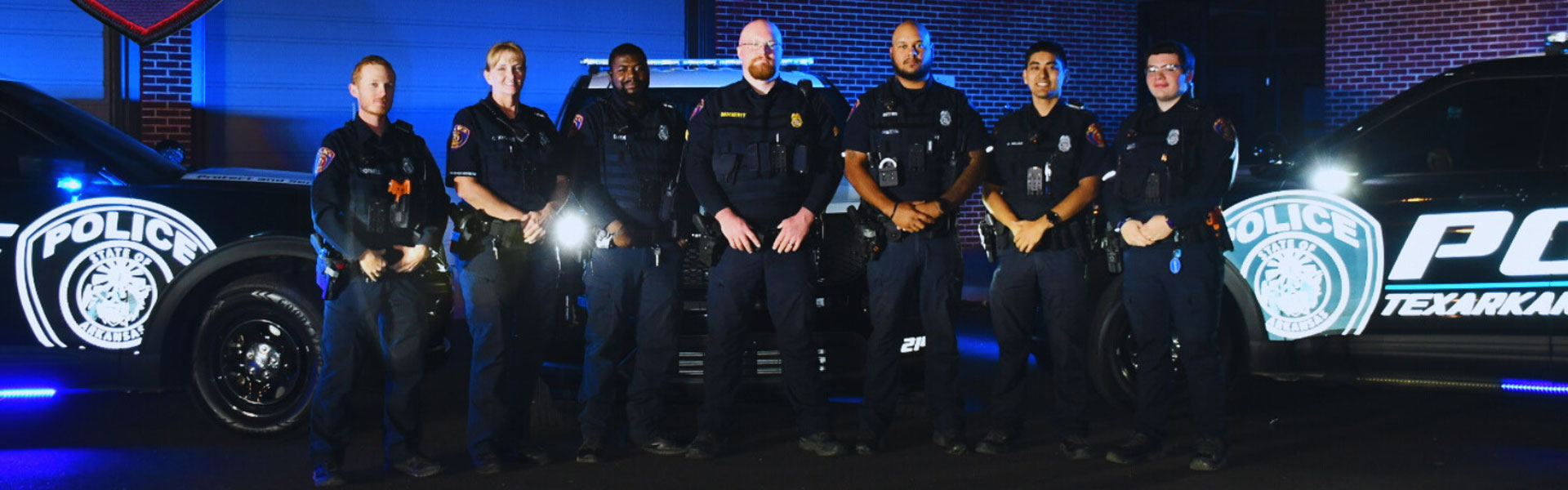 police standing in a row in front of squad cars